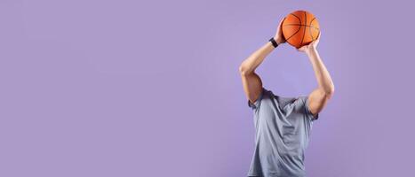 A headless basketball player is poised to shoot, with arms fully extended and holding an orange basketball. photo