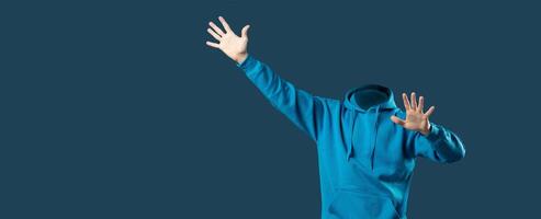 A headless person wearing a blue hoodie stands with arms raised in an isolated background. This collage offers ample blank space for creative use and highlights an intriguing lifestyle concept. photo