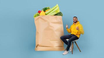 A customer sits with a large paper bag filled with fresh fruits and vegetables. The backdrop is a solid light blue, capturing the joy of online grocery shopping and delivery during current times. photo