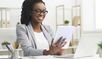 Business App. Afro Woman Using Tablet And Laptop Computer In Office. Free Space For Text photo