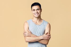 Handsome attractive muscular guy model or blogger and real emotions. Smiling friendly man in casual with crossed arms looking at camera, isolated on light background, empty space, studio shot photo