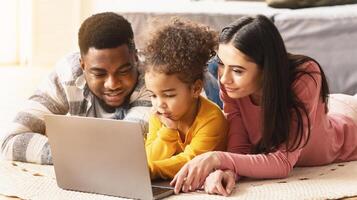International parents teach child to use computer lying on the floor photo