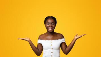 Choice Options. Happy black woman comparing variants, making scales with his palms, holding invisible objects in hands, showing advantages and disadvantages, posing over yellow background, copy space photo