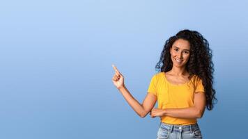 Special Offer. Beautiful millennial woman pointing at copy space over purple background, showing with finger free place for your design, looking and smiling at camera, advertisement template, panorama photo
