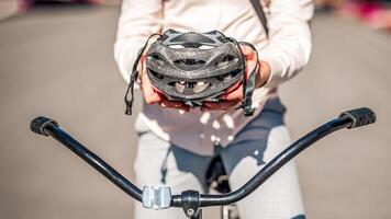 Protection from injuries in city. Guy on bike holds safety helmet in hands on road, cropped, copy space photo