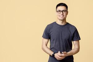 Concept of people, youth, emotions. Smiling attractive young student blogger guy in glasses with smart watch in casual looks at camera, isolated on light background, empty space, studio shot photo