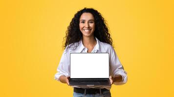 Check This Website. Happy Woman Holding Laptop Computer With Black Blank Screen, Isolated Over Yellow Background, Mockup Image With Copy Space, Template For Your Design, Free Place For Advertisement photo