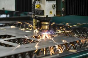 Laser cutting machine creating sparks while processing metal sheet photo