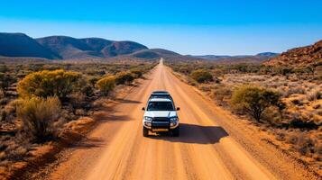 White pickup truck driving on a dirt road in the australian outback desert photo
