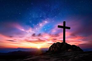 Christian cross standing on mountain top at sunset with milky way galaxy in background photo