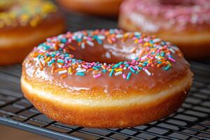 Delicious donut with pink frosting and colorful sprinkles cooling on a wire rack photo