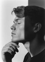 Contemplative portrait of a young man in natural light indoor setting black and white photography photo