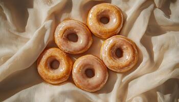 Delicious glazed donuts on soft fabric indoor setting food photography cozy atmosphere top down view photo