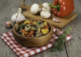 Rustic mushroom and bell pepper dish presentation on wooden table setup photo
