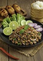 Delectable Thai Larb Moo Presentation with Accompaniments on Rustic Wood Surface photo
