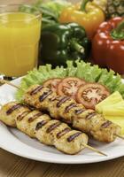 Appetizing chicken skewers with refreshing juice and colorful vegetable garnishing photo