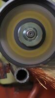 Cutting a metal pipe with an angle grinder creating bright sparks, close-up view of worker's gloved hand operating a powerful grinding tool during industrial fabrication process video