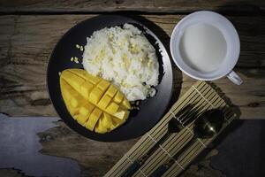 Mango sticky rice, a Thai dish with an old wooden backdrop. This is very popular. photo