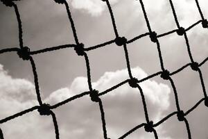 Abstract monochrome goal net with cloud background. Panorama landscape of knot rope in balck and white. Shadow and silhouette. Sports and entertainment. Textured Wallpaper. Copy space photo