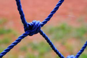 Macro Blue plastic rope knot. Closeup shot of knot rope of goal net. Knots and braids. Sports and entertainment. Textured Wallpapers. Copy space. Bokeh shots. Graphic Design photo