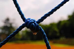 Macrophotography Blue plastic rope knot. Closeup shot of knot rope of goal net. Knots and braids. Sports and entertainment. Textured Wallpapers. Text space. Bokeh shots. Graphic Design photo
