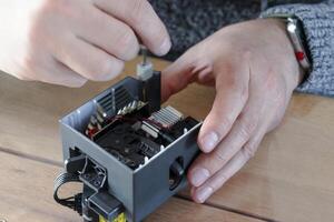 Man dismantling an electrical component for repair, finger photo