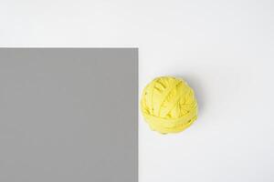 Yellow ball of fabric and gray cardboard. Flat lay, white background. Trending colors of 2021, copy space photo