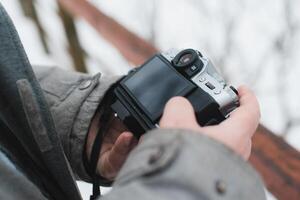 A person holding a camera in front of a snowy background photo