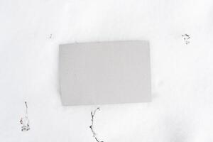 Gray cardboard mock up. Blank sheet of cardboard lying in the snow, top view. Empty space for text, branding, message. photo