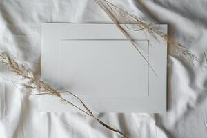Horizontal blank sheet paper and dry spikelets on white cloth, flat lay. Creative mood mockup, copy space. photo