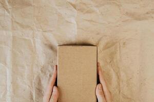 Male hands holding cardboard box. Top view, layout. Delivery concept. Place for text, logo, ads photo