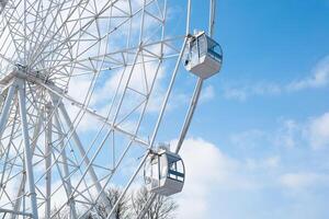 Attraction Ferris wheel in the park against the background of the cloudy sky. Bottom view photo