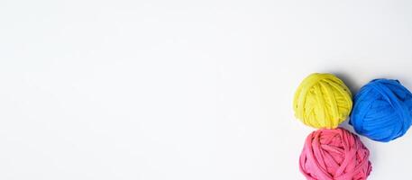 Multicolored rag balls on a white background. Recycled material for knitting blankets. Flat lay banner, copy space. photo