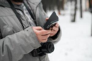 A man holding a cell phone in the snow photo