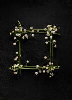 Flower composition. square frame of flowers lilies of the valley on a black background. Flat lay, top view, copy space. Springtime photo