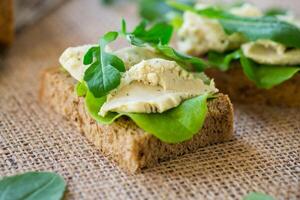 Homemade rye bread with herring paste and arugula on a burlap tablecloth photo