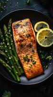 Grilled salmon fillet served with fresh asparagus and lemon slices on a plate photo
