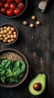 Healthy ingredients including avocado, spinach, chickpeas, and tomatoes on a rustic surface photo