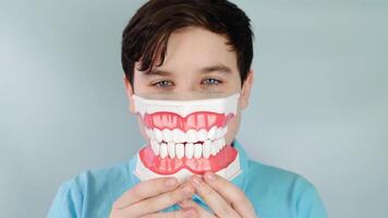 Smiling playful boy demonstrates large denture model with detailed tooth structure video