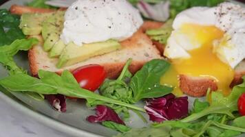 Breakfast delight. poached eggs with avocado on toast and fresh greens video