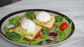 Gourmet breakfast. poached eggs on avocado toast with fresh salad video