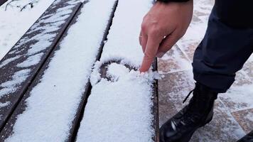 Hand drawing heart shape in snow on bench captures winter's playful essence video