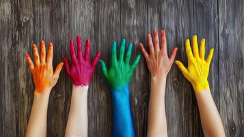 Hands with different colors of paint on them, on a wooden background. 8 photo