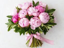 Beautiful bouquet of peonies wrapped with a pink ribbon photo