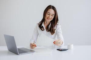 Woman reviewing documents at a modern desk in a bright office setting during the day photo