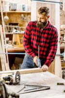 Woodworker crafting furniture in a workshop with tools during daylight hours photo