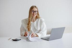 Young woman reviews paperwork while working at a minimalistic desk during daylight hours photo