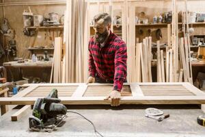 Skilled carpenter assembling a wooden door in a workshop during daylight hours photo