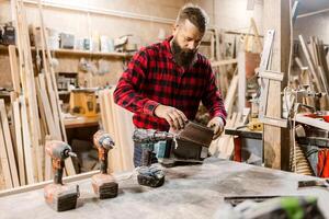 Craftsman working on wood project in workshop with tools and materials during daylight hours photo