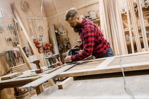 Skilled craftsman working in a woodworking shop on a project using a power tool photo